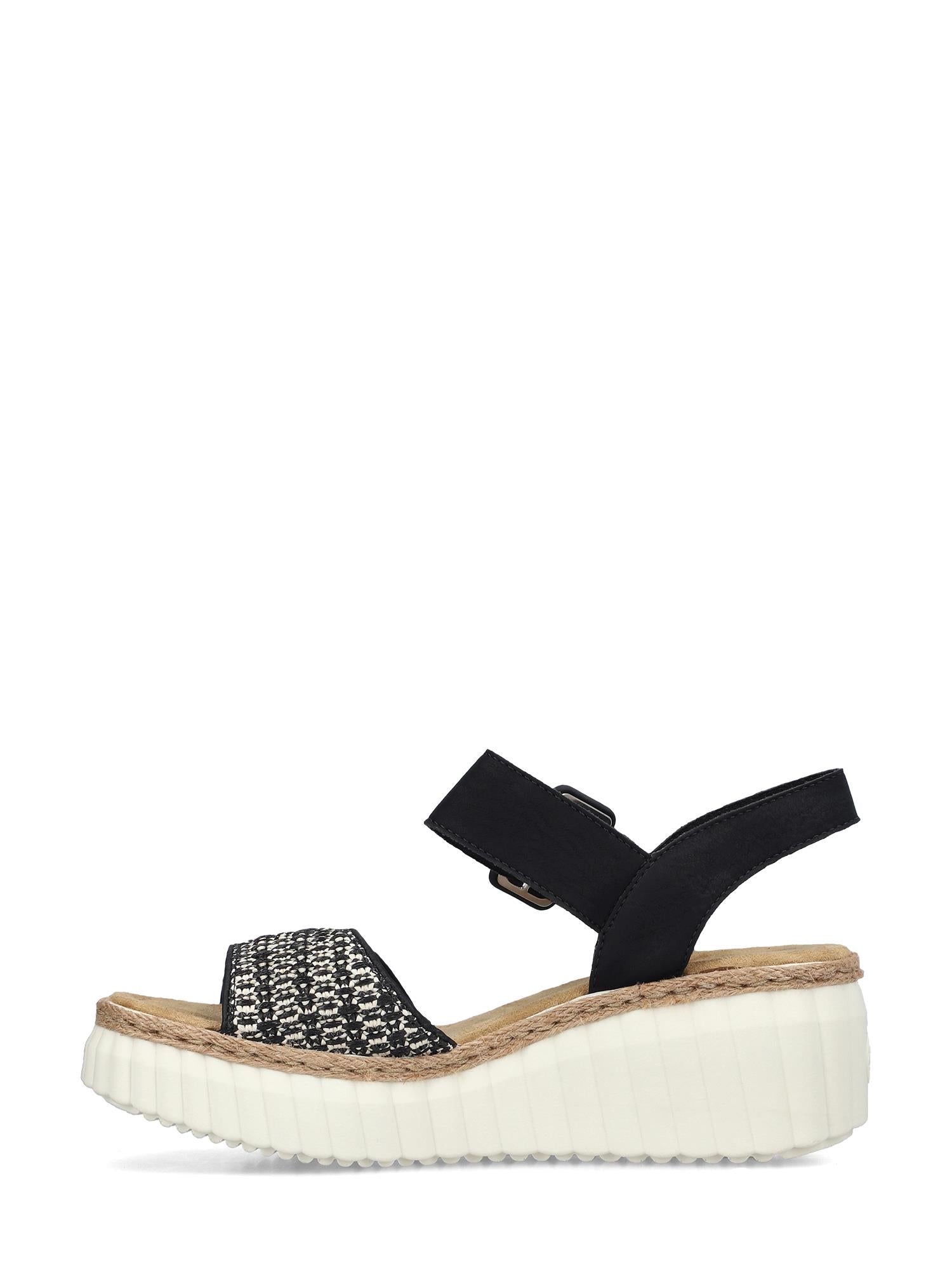 03025 Rieker Celensa Sandal fra Rieker Comfort & Style er en svart damesandal med vevd tårem, justerbar ankelrem, tykk hvit riflet platåkile, lysebrun Antistress-innersåle og komfortbredde G for ekstra komfort.