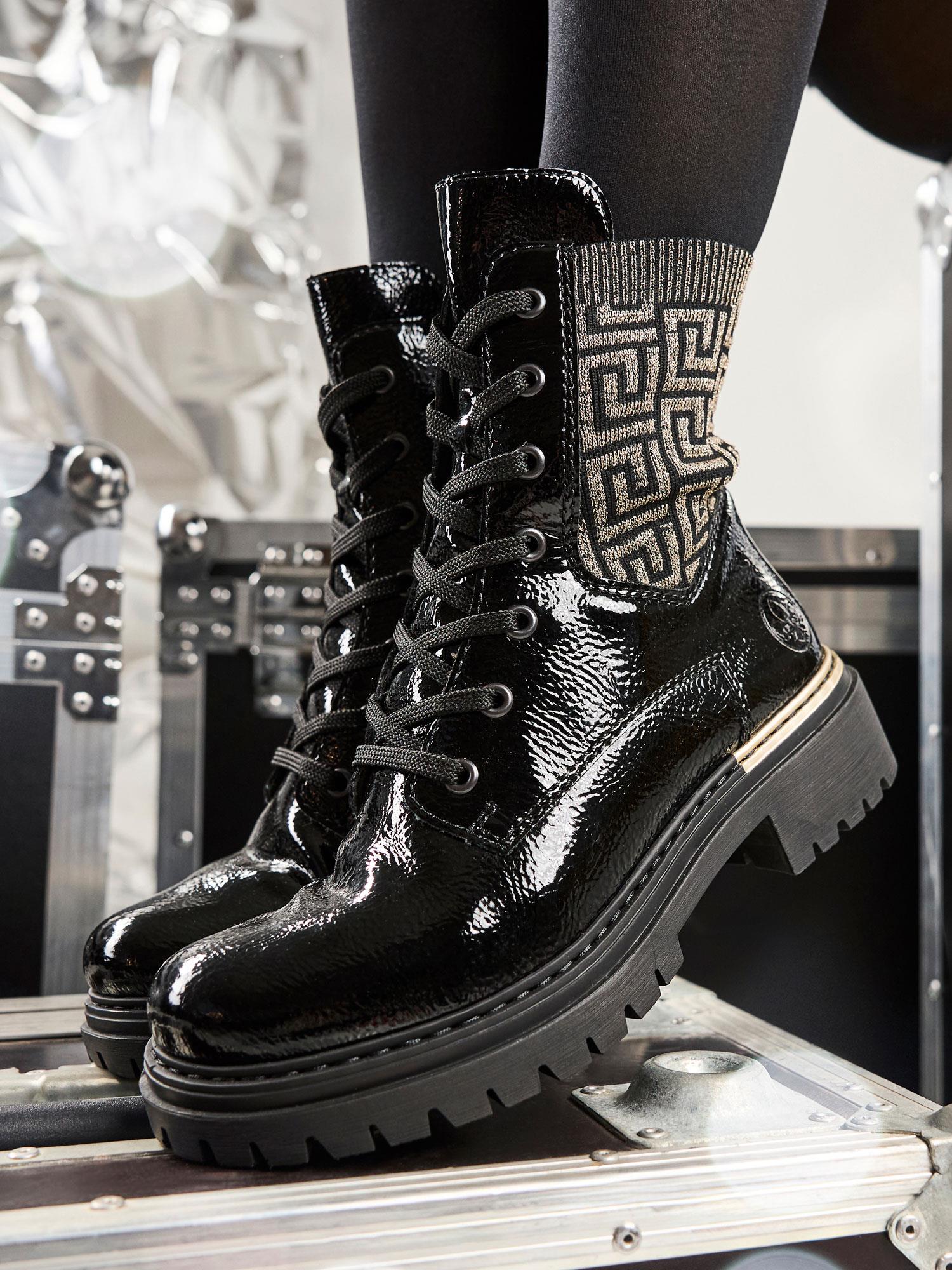 04740 Rieker Artemis Zip Boots fra Rieker Comfort & Style har skinnende, metallic-mønstret stoff og robuste såler. Stylet med svarte strømpebukser mot metalliske og svarte utstyrsvesker, fremhever de disse komfortable dameskoene for en dristig look.