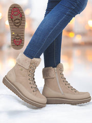 En person iført Remonte 04803 Premium leather tex nude ullfôret støvler med glidelåser på siden, snørebånd og røde sålegrep står på snø. Støvlene har pelsfôr og brodder, og er matchet med blå jeans.