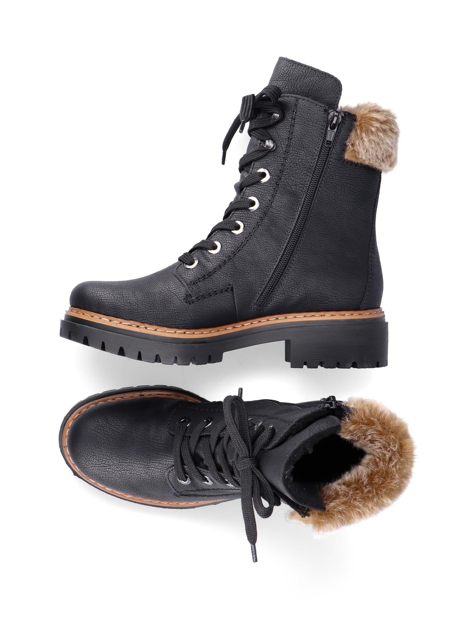 Et par Rieker Comfort & Style 05377 pelsstøvler i svart, med snøring foran, glidelåser i siden, tykke såler med mønster og plysj pelskant ved anklene, vist fra siden og ovenfra mot en hvit bakgrunn.