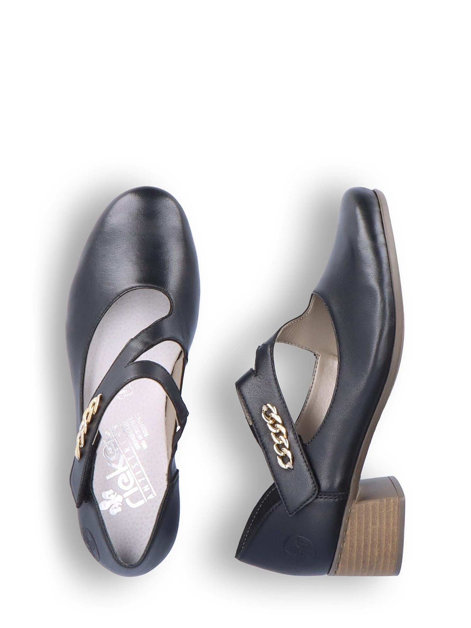 Et par Rieker Comfort & Style 06819 Cross over Pumps i svart skinn med lave blokkhæler, kryssende reimer, skinnsåle og gullkjededetaljer på reimene, vist mot en hvit bakgrunn.