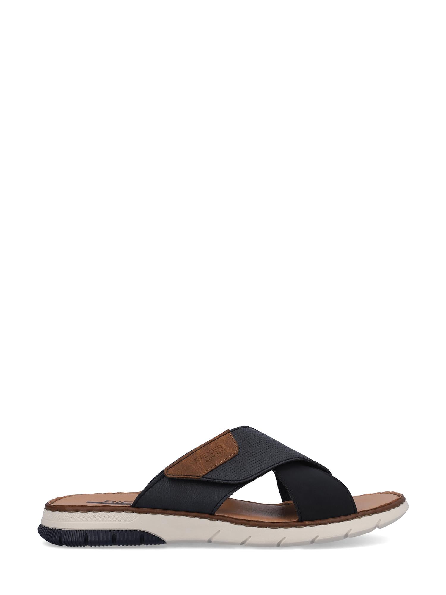 08047 Rieker Lake sandal fra Rieker Comfort & Style har svarte, kryssende kunstlærremmer, en brun fotseng, beige lappedetaljer og en hvit såle med svarte mønsterdetaljer, vist i sideprofil mot en hvit bakgrunn.