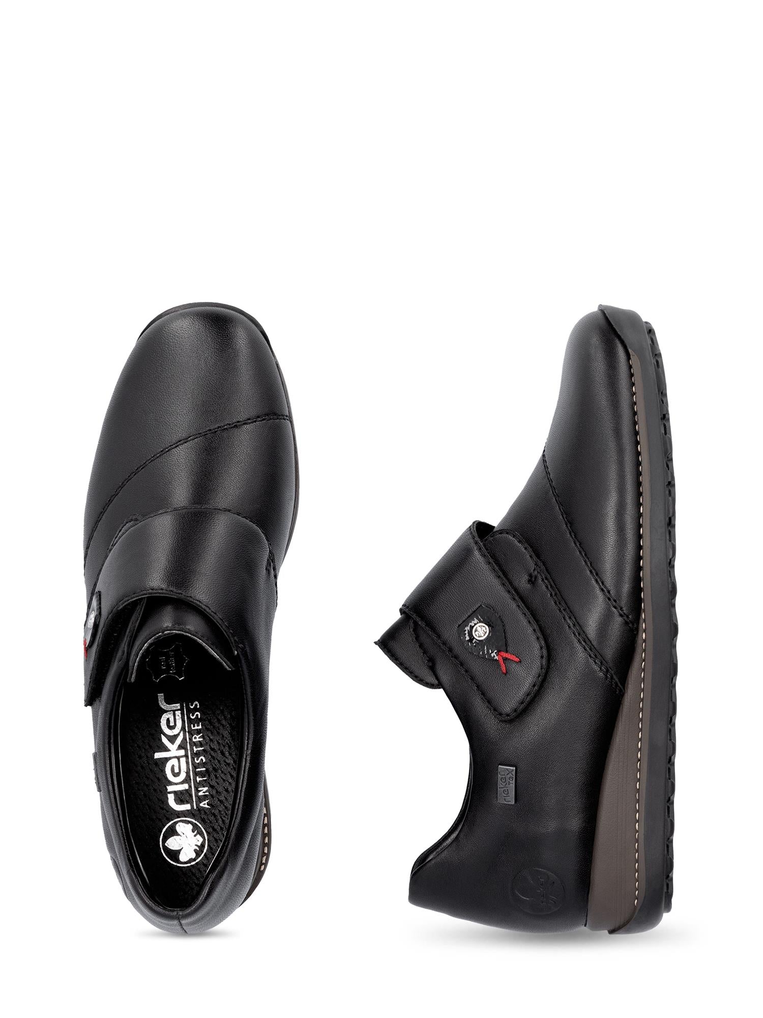 Et par svarte 04996 Rieker Leather Tex-membran slip-on sko fra Rieker Comfort & Style i svart skinn, med borrelåsstropp, rund tupp, støtdempende såle og logo på innersåle og stroppen. Vist ovenfra og fra siden.