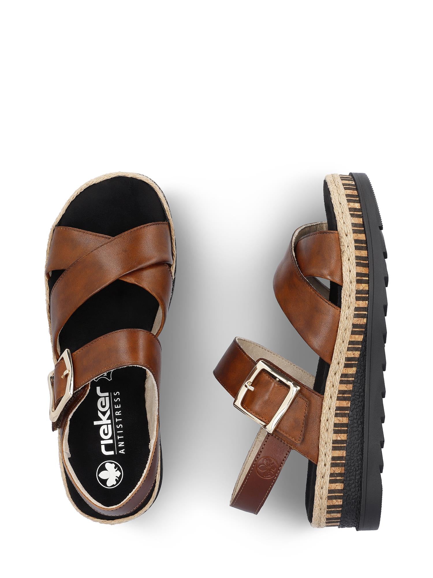 07520 Rieker Arizona Sandal fra Rieker Comfort & Style har brunt skinn, kryssreimer, ankelspenne og en platåsåle med stripete, strukturert bunn. En sandal er vist ovenfra og en fra siden.