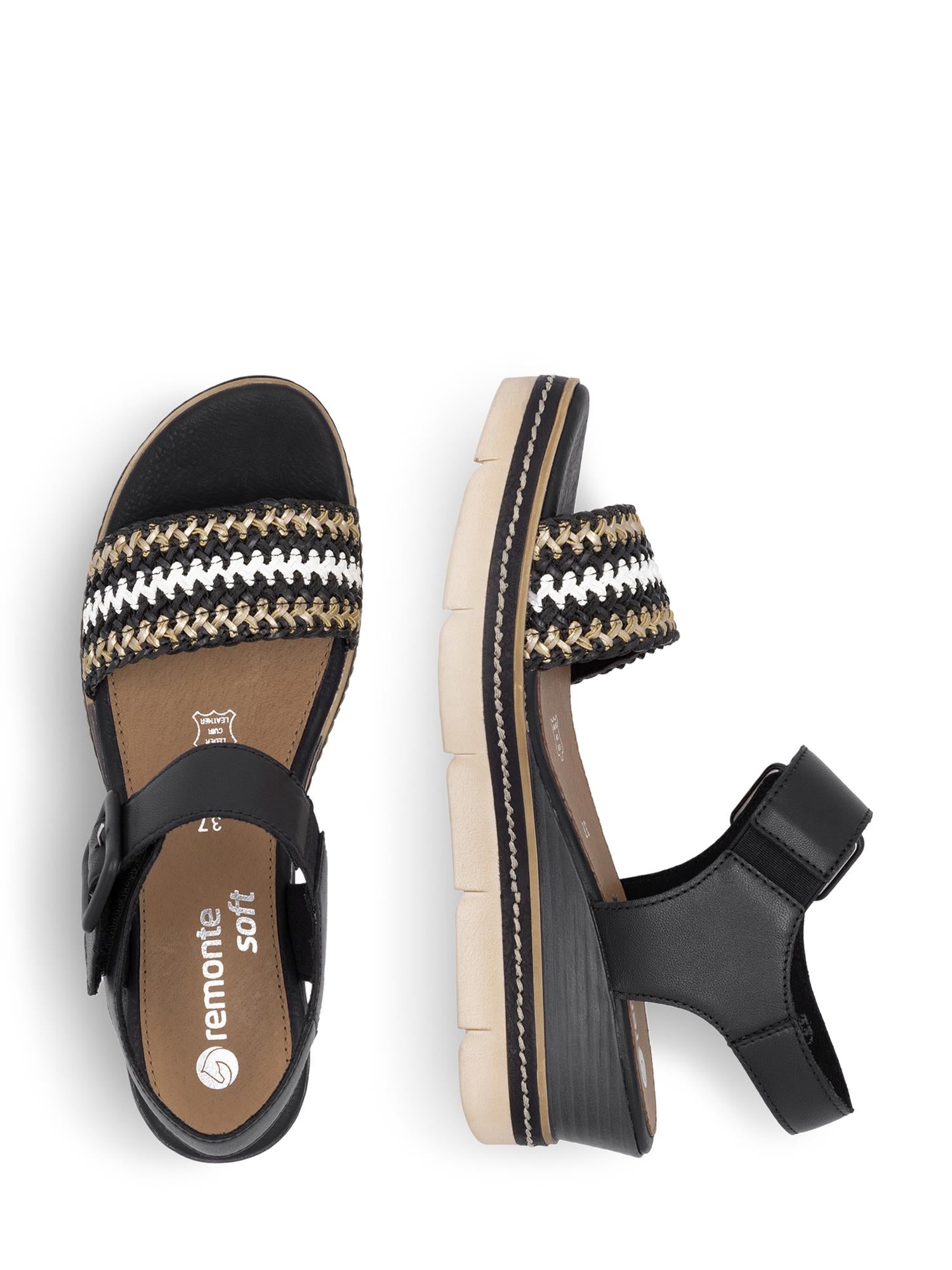03146 Remonte Alvora Sandal fra Remonte er en svart damesandal med en kraftig beige såle og vevde remmer i svart, hvitt og beige. Den ene sandalen er vist ovenfra, den andre fra siden for å vise platehælen og ankelremmen med spenne.