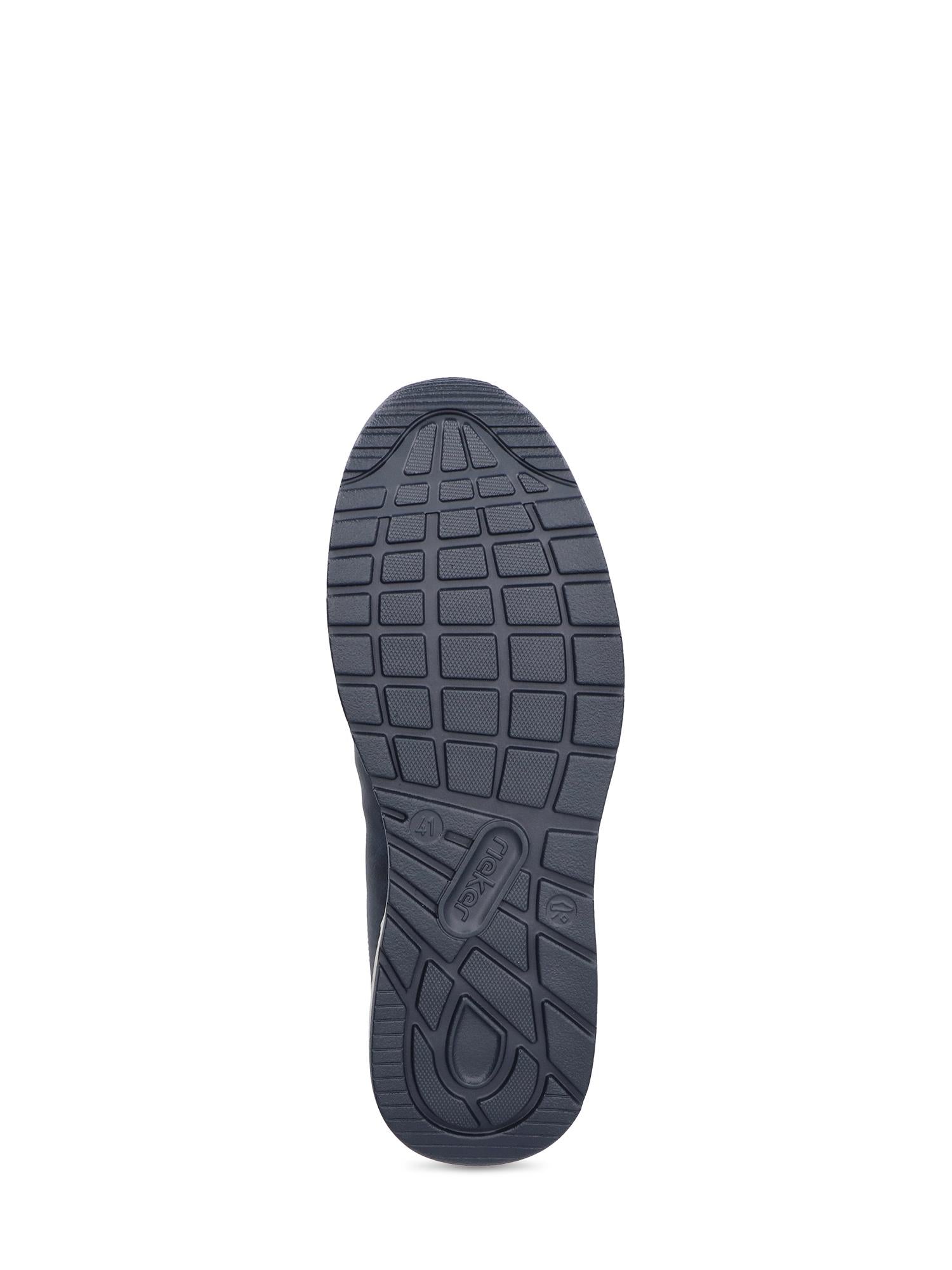 Bildet viser den svarte gummisålen på 03051 Rieker Nolan Slip-on fra Rieker Comfort & Style, med et strukturert, rutenettlignende mønster som gir grep og komfort. "Rieker" er preget nær midten nederst. Bakgrunnen er hvit.