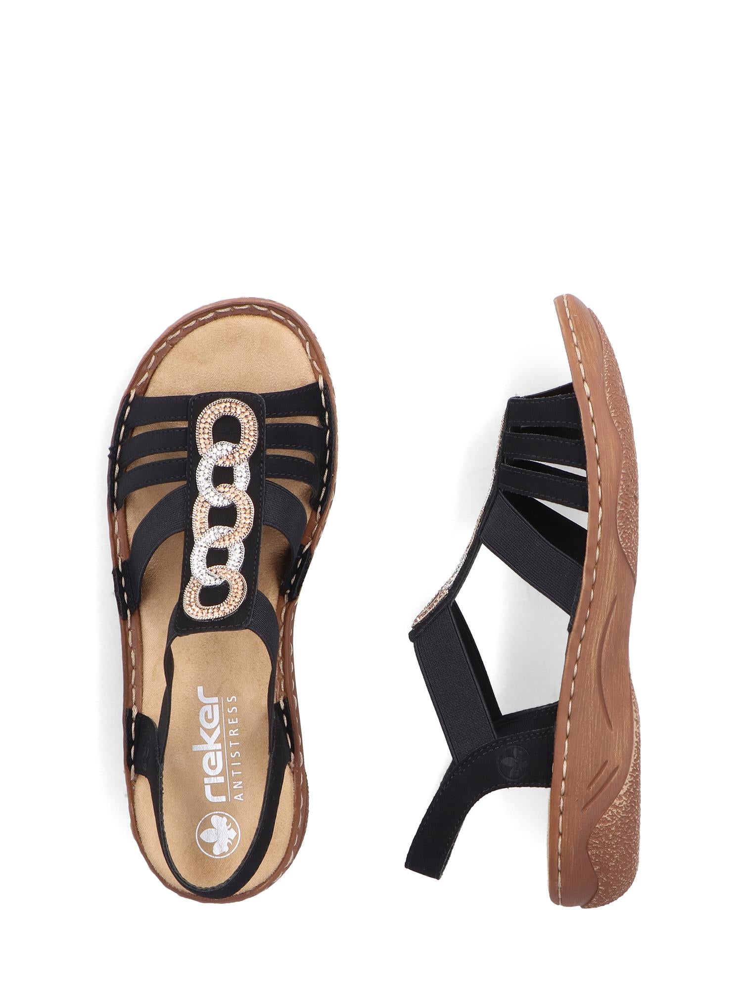 Et par svarte 03344 Rieker Leona Sandals fra Rieker Comfort & Style med solbrune såler, dekorative metallringer på remmen, elastiske reimer, synlige sømdetaljer og en liten passform for ekstra komfort.