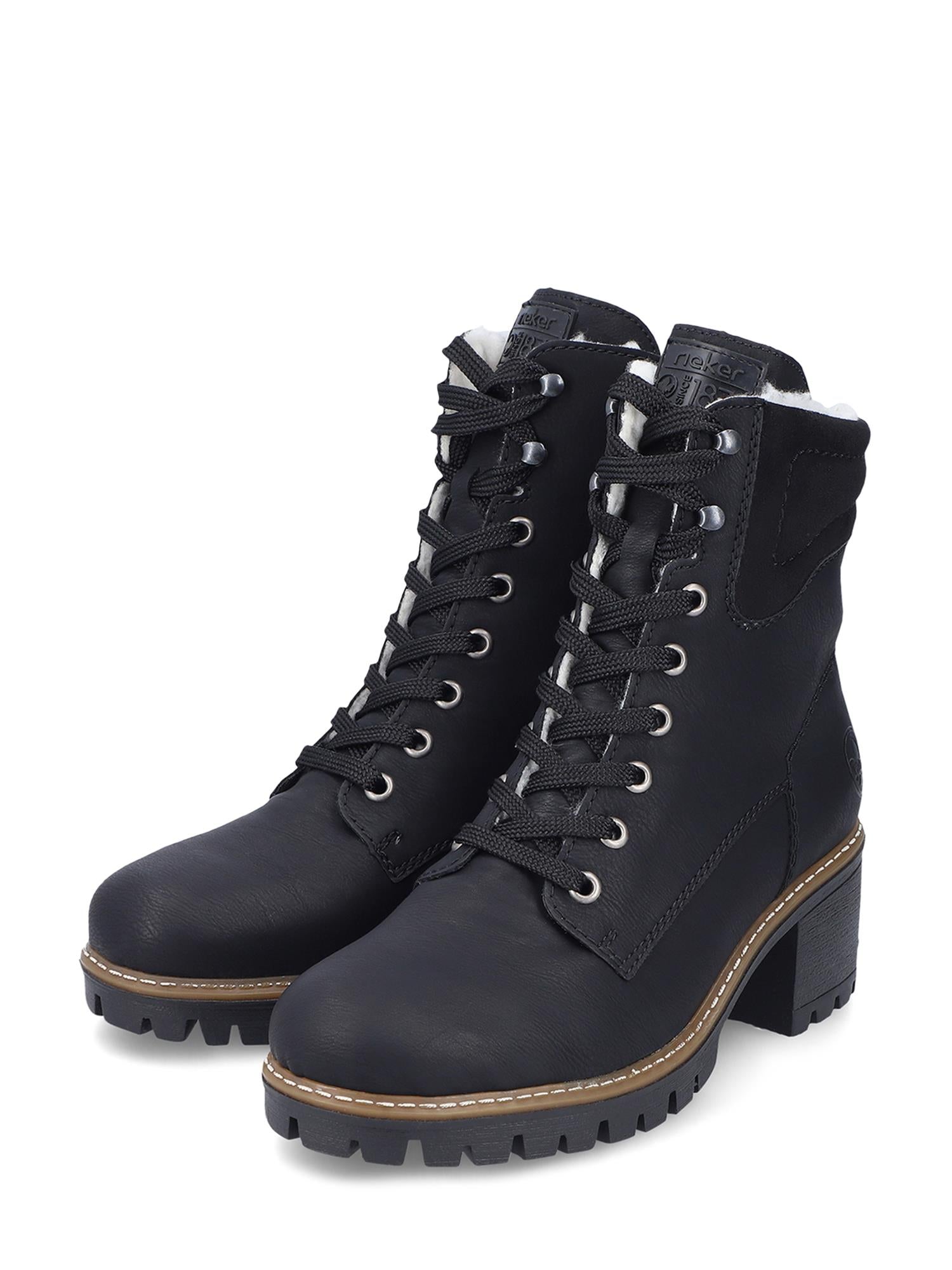 04738 Rieker Warm-lined Boots fra Rieker Comfort & Style er svarte snørestøvler med tykke såler, blokkhæl, sølvfargede maljer, detaljerte sømmer og polstrede krager som gir et robust, men stilig utseende.