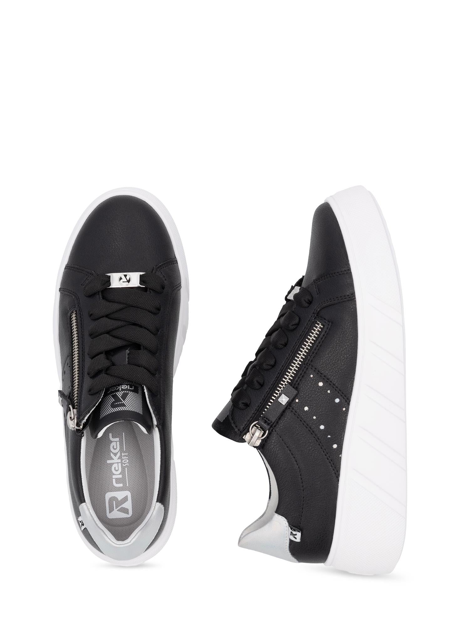 Et par svarte Rieker Sport 03558 Active Platform-sneakers i skinn med antistressteknologi, hvite såler, sølvfargede glidelåser på siden og hvite prikker. Den ene skoen er sett ovenfra, den andre sett fra siden, begge mot hvit bakgrunn.
