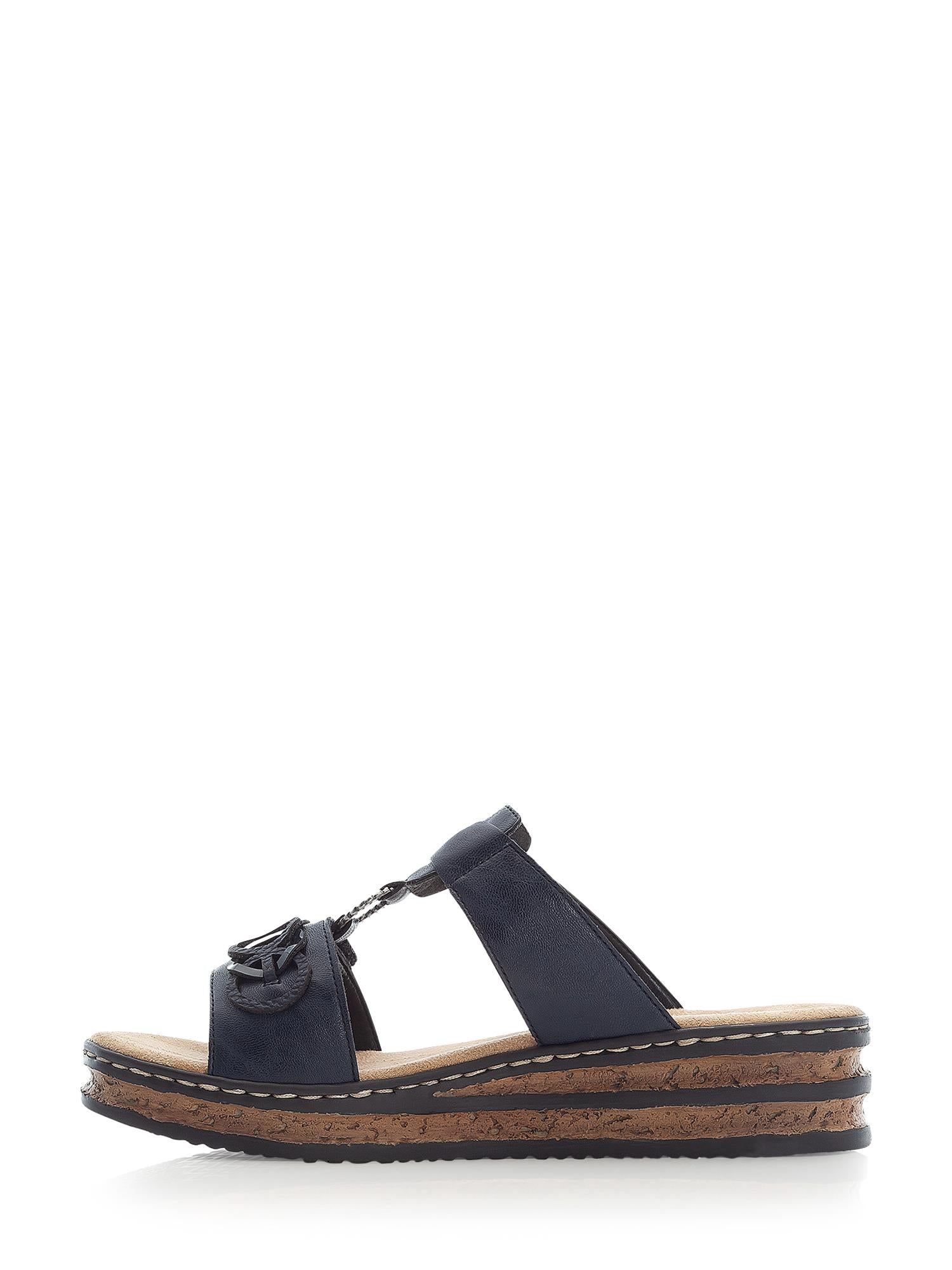 02996 Rieker Pacific Dream Sandal fra Rieker Comfort & Style er en marineblå sandal med en lav korkkile, brune sømmer og svart spenne på de øvre stroppene, vist fra siden mot en hvit bakgrunn.